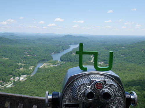  TU Logo on binoculars with a view on a river landscape