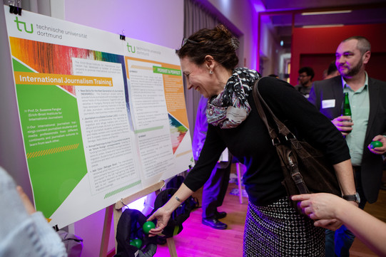 one person looks at the poster on display, another person stands in the background 