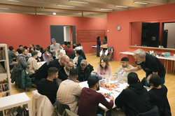 Teilnehmende des Sprachcafés sitzen an Tischen und spielen Karten- und Brettspiele.