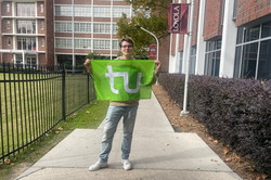 Hier sieht man den Studenten, wie er vor der Loyola University die TU Flagge hochhält.