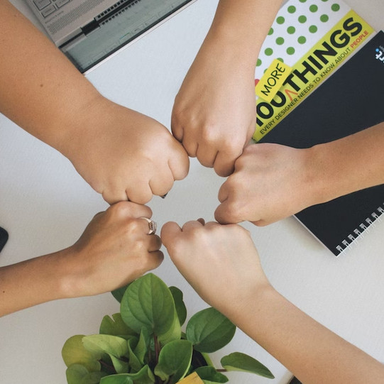 Diverse people hold their fists to each other as a sign of unity. 