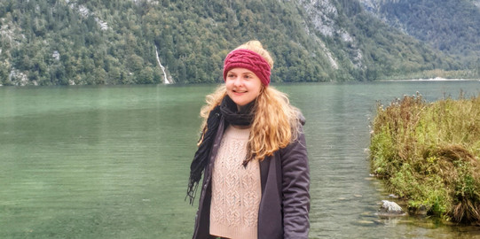 Eine Person steht auf einem Steg und lächelt in die Kamera.