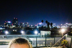 Willi lacht in die Kamera auf einem Dach über einer Stadt