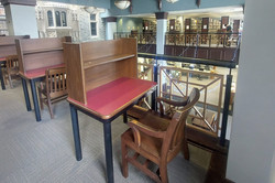 Hier sieht man Lernplätze in einer Bibliothek. Sie bestehen aus einem Holzstuhl und -tisch.