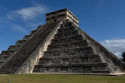 Man erkennt einen großen Maya Tempel. Der Himmel ist blau. 