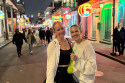 Hier sieht man die Studentin zusammen mit ihrer Schwester auf einer belebten Straße bei Nacht mit Neonlichtbeleuchtung. 
