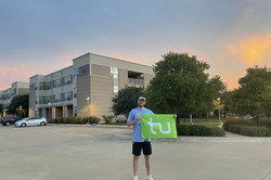 Alessandro S. steht mit der TU-Flagge vor Haus seines Apartments