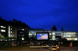 Open Air Cinema Hier sieht man eine Leinwand auf dem Unicampus bei Nacht.
