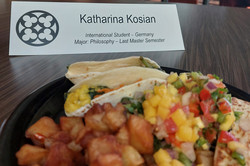 Hier sieht man das Mittagessen der Studentin und ihr Namenschild mit dem Zusatz, dass sie aus Deutschland kommt und Philosophie im Master studiert.