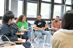 A small group of international students sits in a circle and talks.