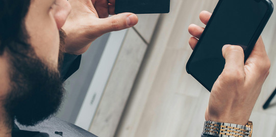 Ein Mann der eine Bankkarte und ein Handy in den Händen hält