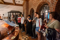 Menschen stehen um die Kupferkessel einer Brauerei.