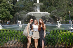 Drei Personen stehen vor einem Springbrunnen.