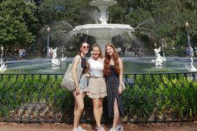 Drei Personen stehen vor einem Springbrunnen.