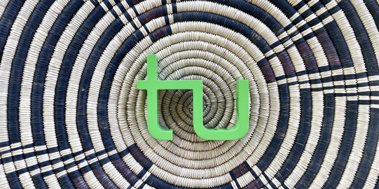 The TU Logo is lying on a basket with a black-brown African pattern