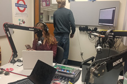 Man erkennt ein Podcast Studio mit vielen Aufnahmegeräten und zwei Tischen. 