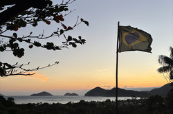 Sicht auf einen Strand beim Sonnenuntergang mit einer brasilianischen Flagge im Vordergrund.