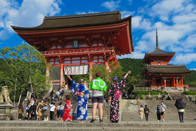 Drei Studierende der TU Dortmund in Kyoto. Von links nach rechts stehen in der Mitte des Bildes: Lisa, Yannik und Dagny. Lisa und Dagny tragen Yukata, traditionell japanische Kleidung. Yannik trägt die TU Dortmund-Flagge.