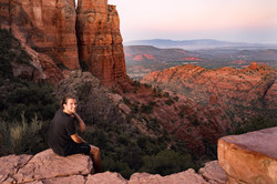 Willi sitzt an einem Abgrund während des Sonnenuntergangs in den Canyons