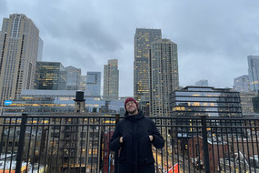 Auf dem Bild sieht man Alessandro S. wie er auf der Hotelterrasse steht und im Hintergrund die Skyline von Chicago