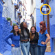 Four persons standing in between blue buildings smiling