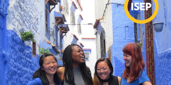 Four persons standing in between blue buildings smiling