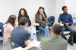 A group of international students sits in a circle and talks.