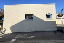 Gebäude/Wand Das Bild zeigt ein kleines Gebäude mit einer blanken Wand und zwei Fenstern.