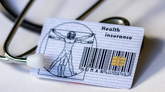 A health insurance card with a stethoscope in the background.