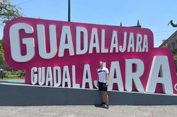 Guadalajara Hier sieht man den Studenten vor einem pink/weißen Schild, auf dem Guadalajara steht.