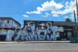 Hier sieht man ein Grafitti, auf dem vier schreiende Männer abgebildet sind.