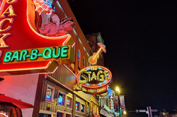 Hier sieht man eine beleuchtete Straße voller Bars und Neonschilder. 