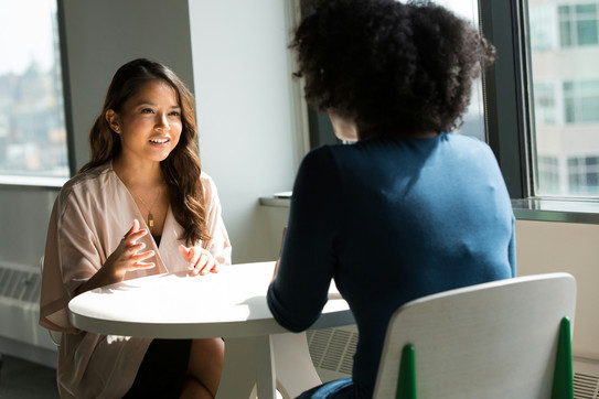 Bewerbungsworkshops: Coaching Zwei Frauen sitzen an einem Tisch und unterhalten sich angeregt. Es handelt sich um einen 1:1 Coachingtermin.