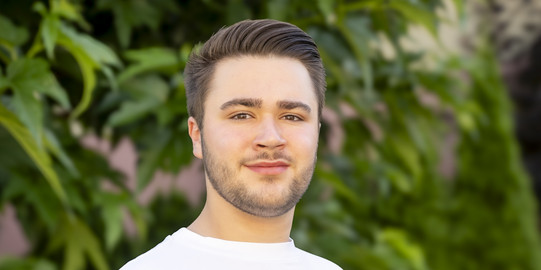 Foto von Benedikt vor Bäumen.