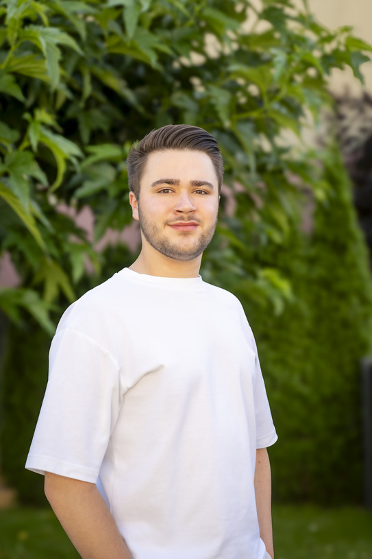 Foto von Benedikt vor Bäumen.