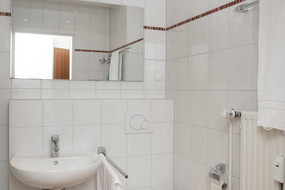 Ein Blick in das Badezimmer eines Gästehaus-Apartments. Man sieht das Waschbecken, einen Spiegel und die Toilette.