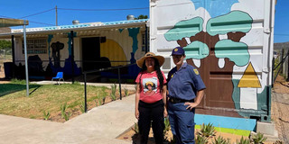 2 people standing in front of a brightly painted building