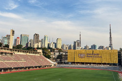 Stadion Das Bild zeigt den Blick auf ein leeres Stadion mit Laufbahn sowie einigen Hochhäusern im Hintergrund.