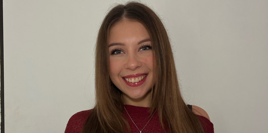 Junge Frau mit rotem Oberteil lächelt in die Kamera