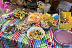 Hier sieht man verschiedene Gerichte, die auf einer bunten Tischdecke angerichtet sind.