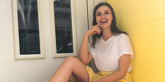 Pauline with a yellow skirt in front of a yellow wall
