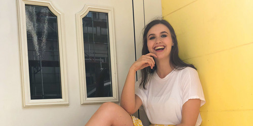 Pauline with a yellow skirt in front of a yellow wall