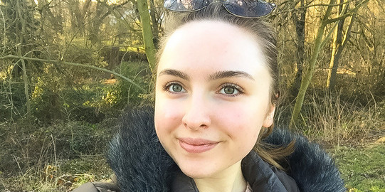 Foto von Katharina im Wald in einer Jacke.