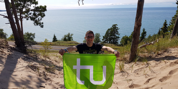 Daniel carrying the TU flag with the Pacific Ocean in the background.