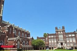 Loyola University Hier sieht man das Unigelände. In der Mitte ist eine große Wiese mit einem "Loyola" Schild und daneben sind zwei altertümlich gebaute Gebäude aus rotem Backstein.