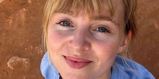 Junge Frau mit blauem Oberteil macht ein Selfie von oben