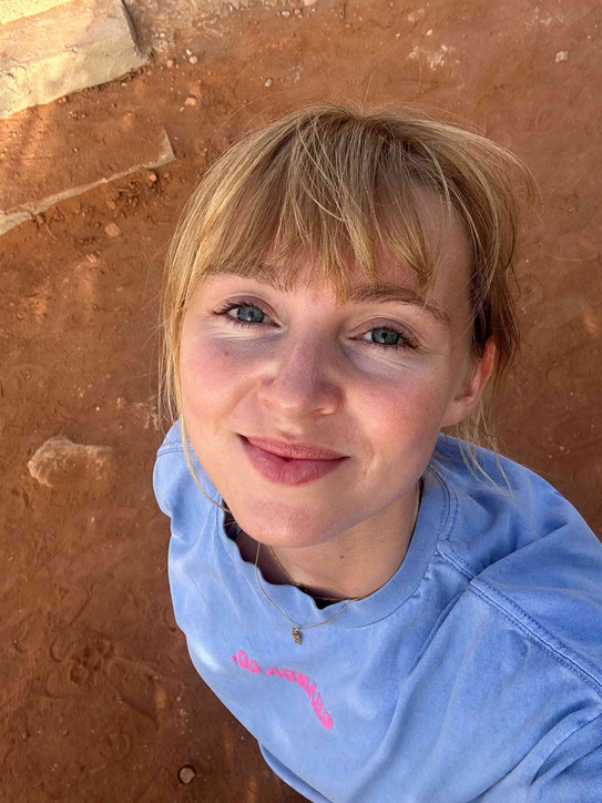 Junge Frau mit blauem Oberteil macht ein Selfie von oben