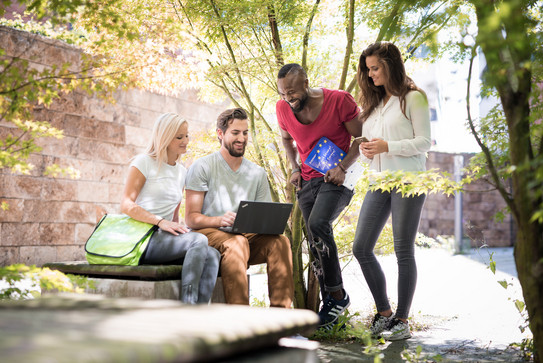 Studierende im Freien mit Laptop und Erasmus+ Werbematerial