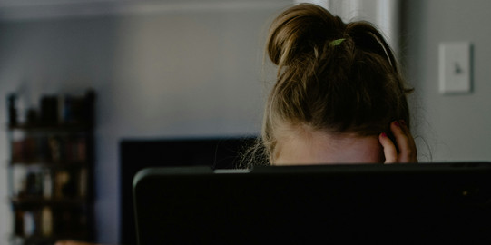 Frau sitzt verdeckt hinter einem Laptop