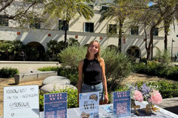 WIL Tabling Man erkennt Carla, die auf dem Campus hinter einem Uni-Stand steht.
